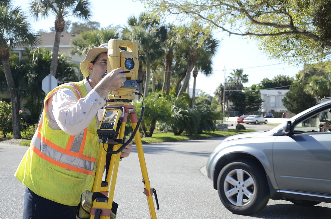 Fred Moser, survey assistant for Sarasota County, collects data on Canal Road.