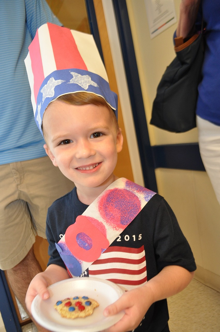 Garrett Rogers, 3, eats a cookie while watching his brother, Grant, parade in the 1-year-old classroom.