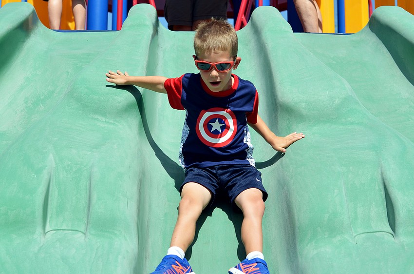Alex Nickel slides down the slide after riding his bike in the GreyHawk Landing Community Parade.