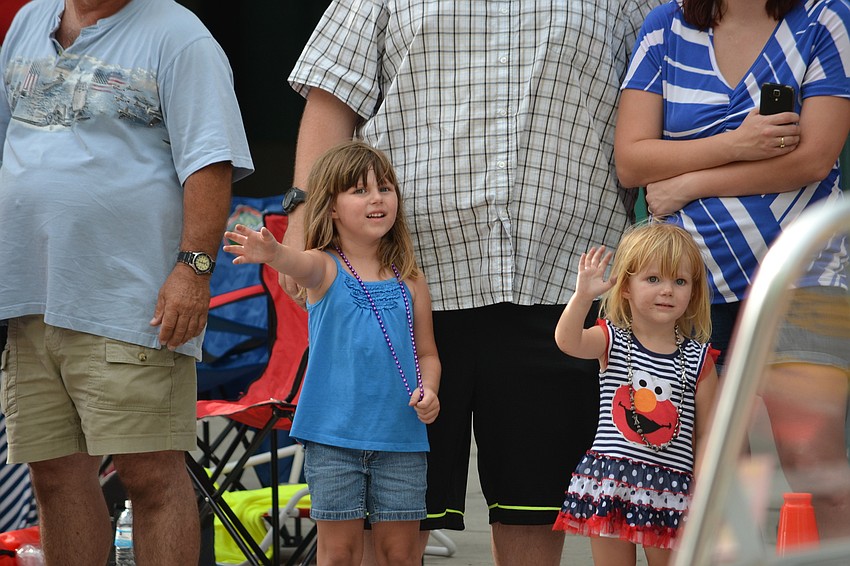 Sisters Abigail and Hannah Jordan wave as boats roll by in the parade.