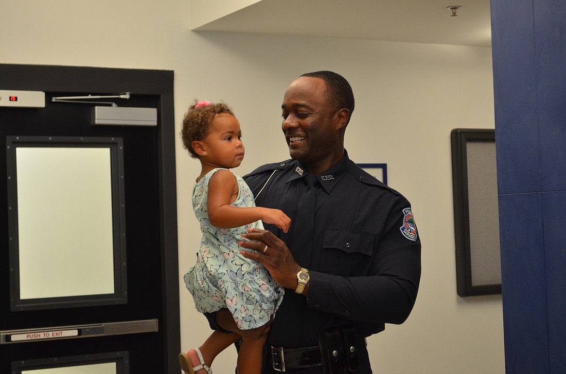 Officer Larry McQueen shares a moment with his daughter before his promotion ceremony.