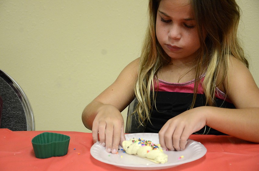 Zoe Korman, 8, puts sprinkles on her Challah bread.