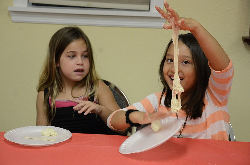 Zoe Korman, 8, and Chaya Steckel, 7, laugh at how sticky their bread dough is.