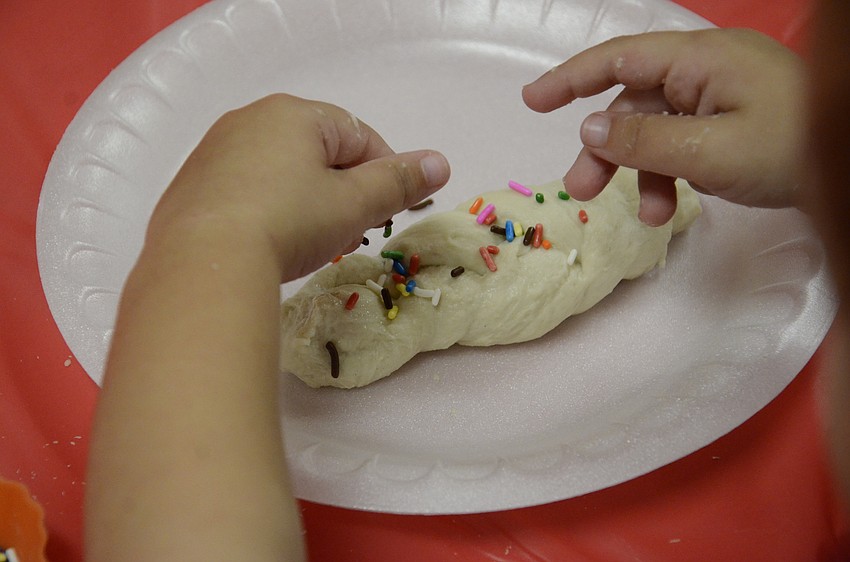 A Gan Israel camper adds some color to his Challah braid.