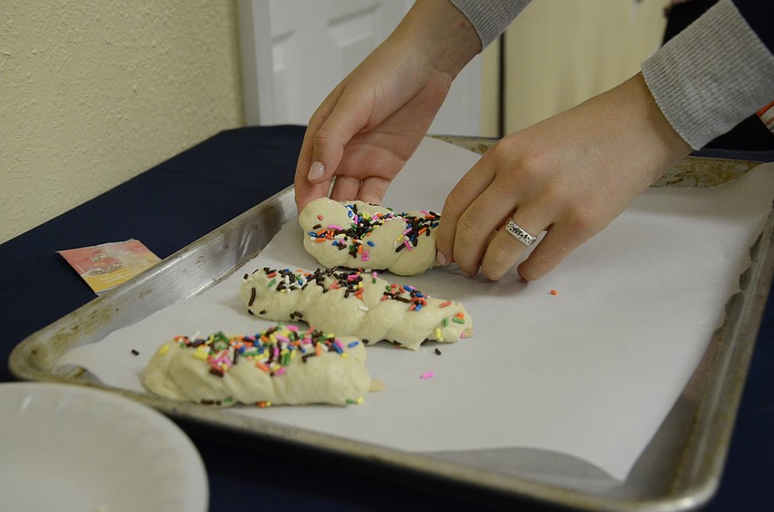 Counselor Ceita Marasow arranges the braids on the baking sheet.