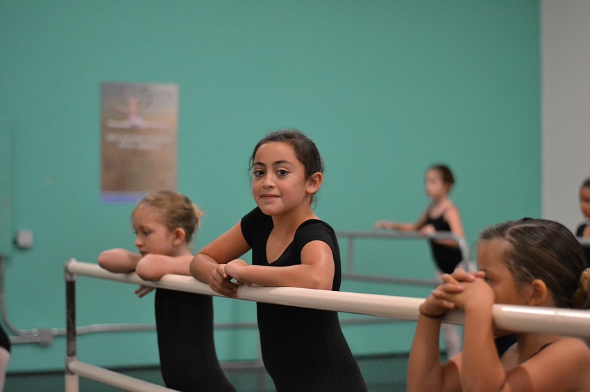 Willa Nance, Valentina Borchart and Chiara Diaz rest on the barre during class.