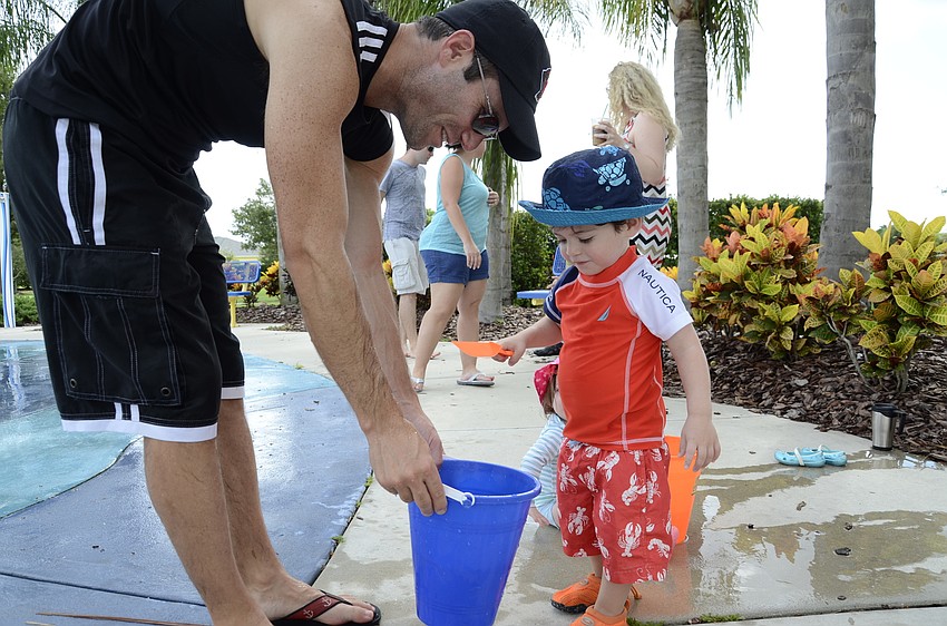 Josh Blazer helps his son, Jake, 1, fill up a bucket.