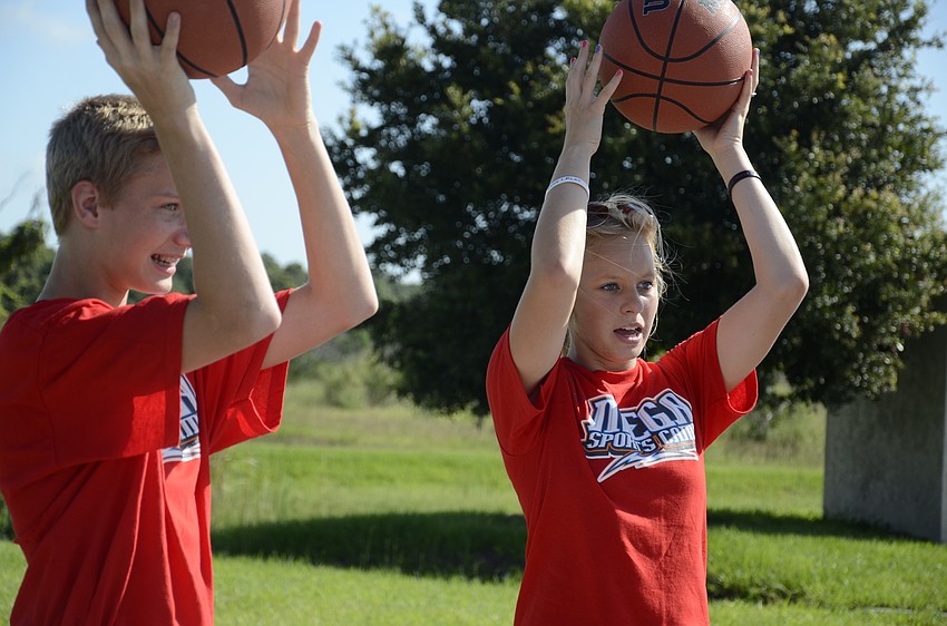 Camp volunteers Jayden Mielke and Jordyn Keranen teach children how to concentrate and handle the basketball.