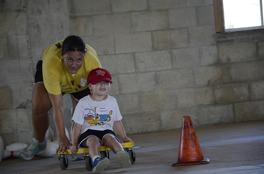 Amanda Hirst pushes Dominic Carrasco in a race.