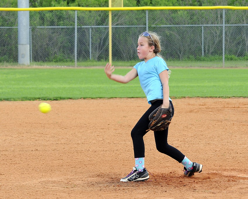 Eight-year-old Grace Shaw throws a pitch during a fielding drill.