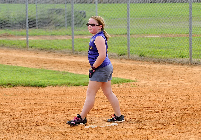 Seven-year-old Aubrey Barak keeps her eye on the pitcher as she leads off from first base.