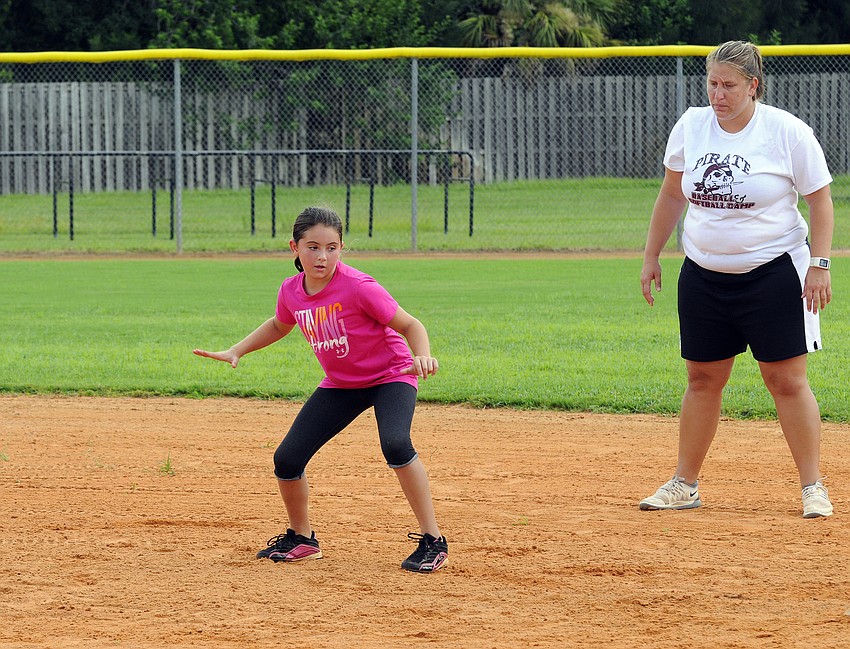 Ten-year-old Ava Barak receives some base stealing advice from Braden River softball coach Melissa Dowling.
