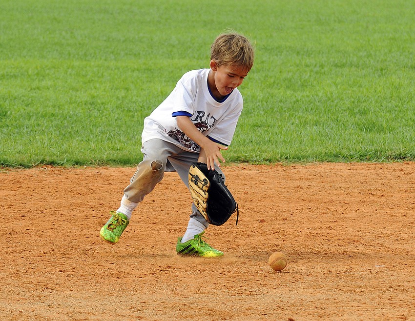 Six-year-old Matthew Vanderzee retrieves a ground ball during a fielding drill.