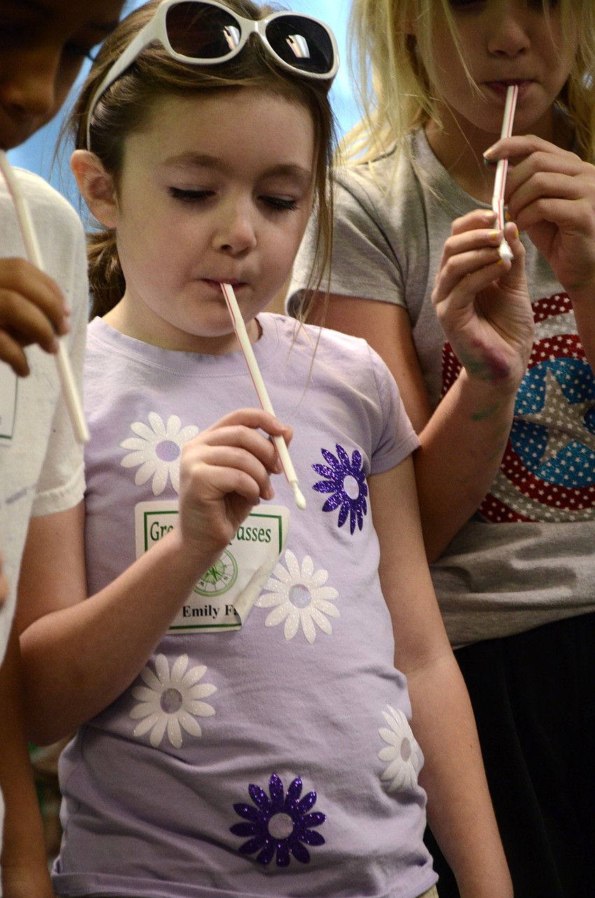 Emily Fay tries to shoot a cotton swab and hit a target on the floor.
