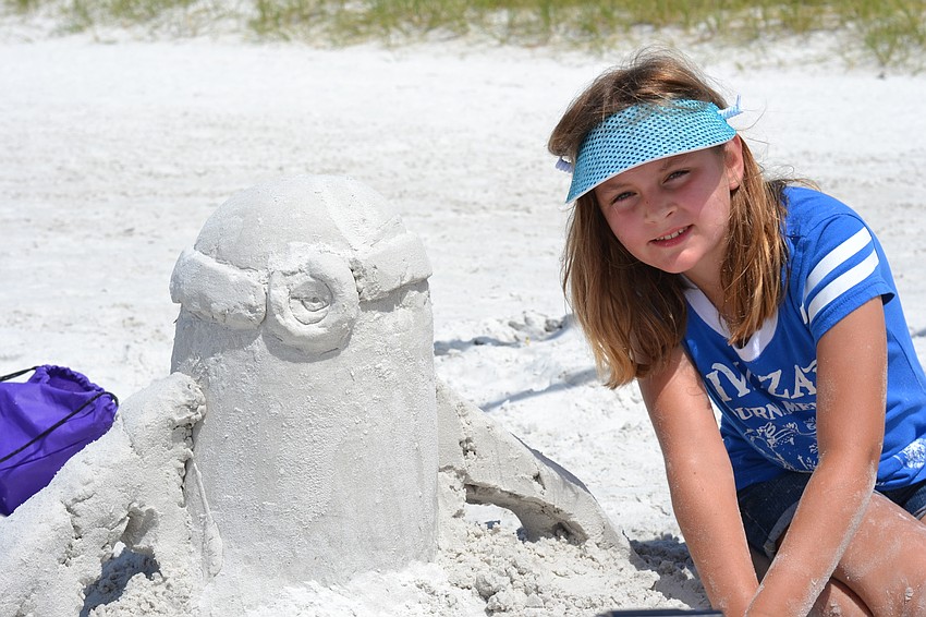 Katie Gray poses with her sculpture of a minion from the movie 