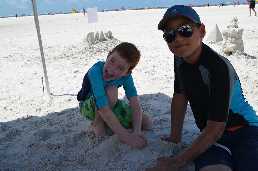 Stewart McLain and Even Lei play in the sand after completing their sculptures.