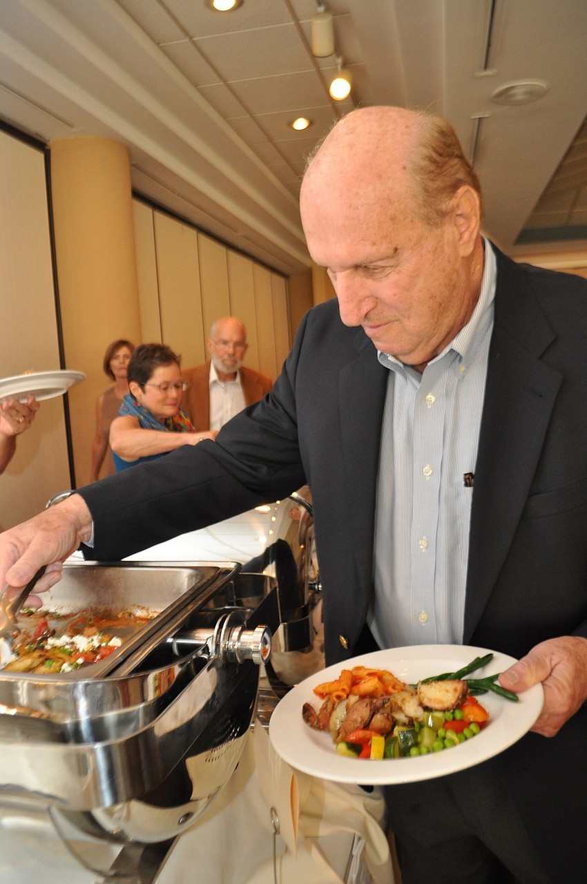 Matt Bornstein fills his plate with a variety of buffet options, such as chicken, green beans, penne, and more.