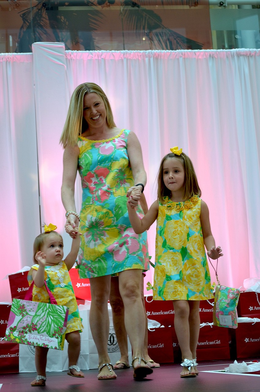 Vanessa Heuss (center) guides her daughters, Clara and Anna, toward a crowd during the fashion show.