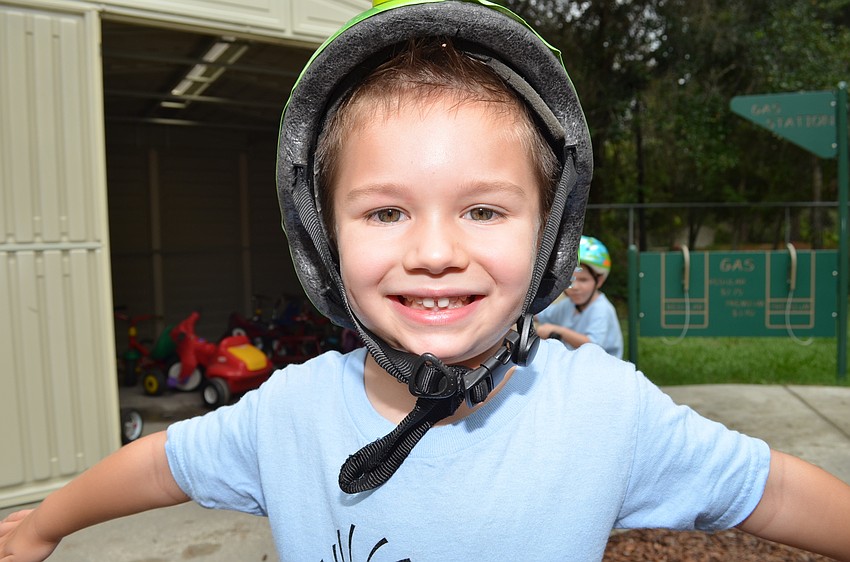 Cal Nykorchuck straps on his helmet before riding a tricycle.