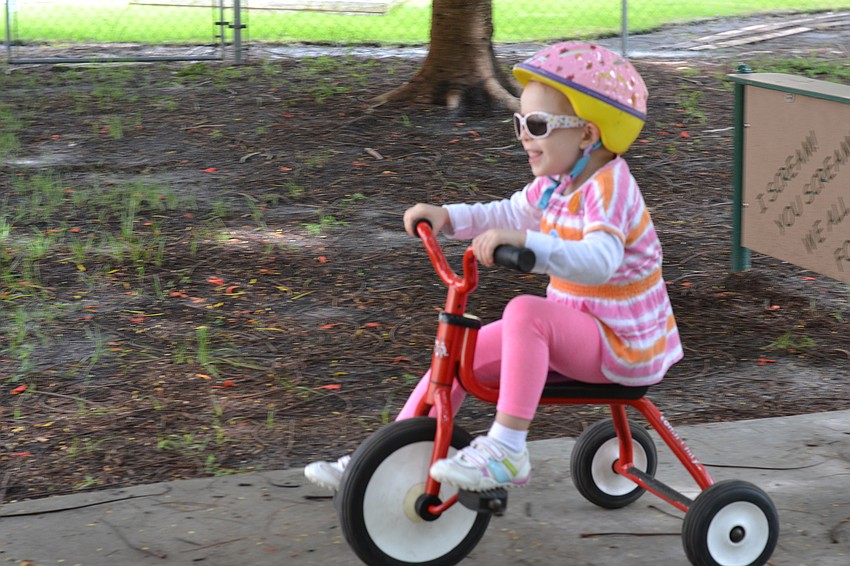 Elisa Wriston speeds around the corner on her tricycle.