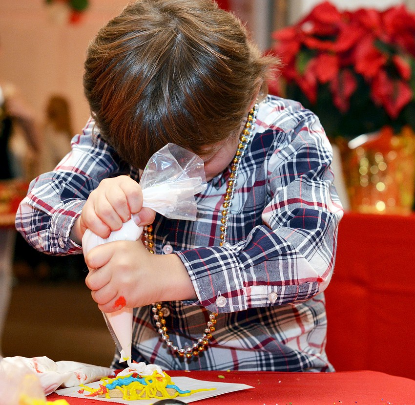 Colt Chalmers decorates a Christmas tree cookie at Christmas in Candyland.