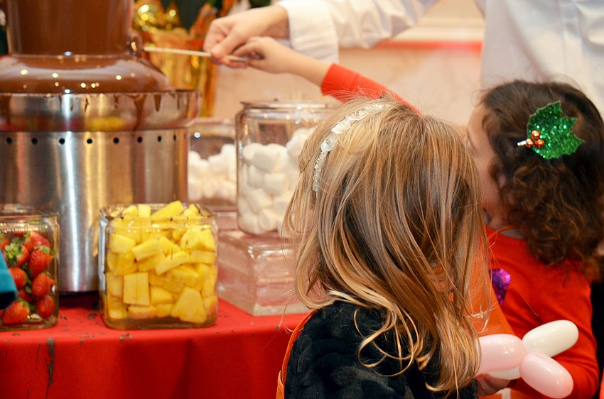 Kids dip marshmallows and fruit in the chocolate fondue foundation at Christmas in Candyland.