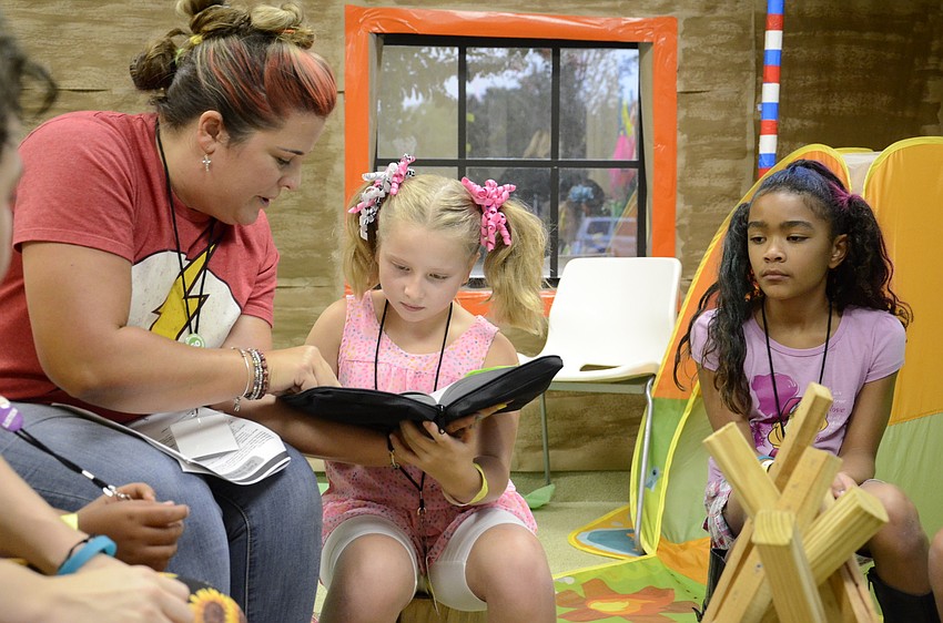 Volunteer Betsy Prunty helps her daughter, Madison, read a Bible passage.