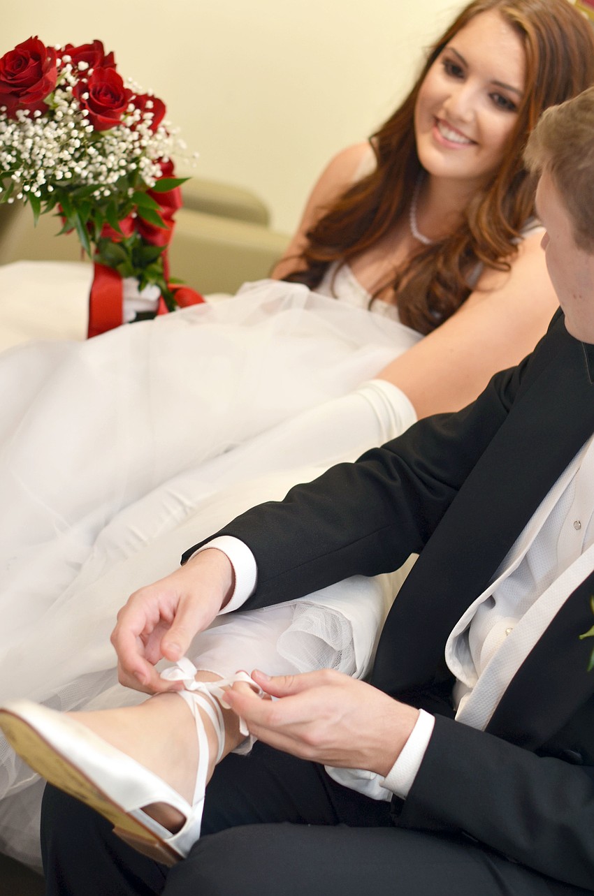 Serena Shabetaiâ€™s escort Connor Borden helps her with her shoes before The Debutante Ball.