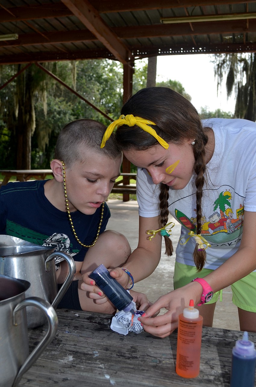 Jon Juallen watches as Jamie Glass helps him dye a bandana.