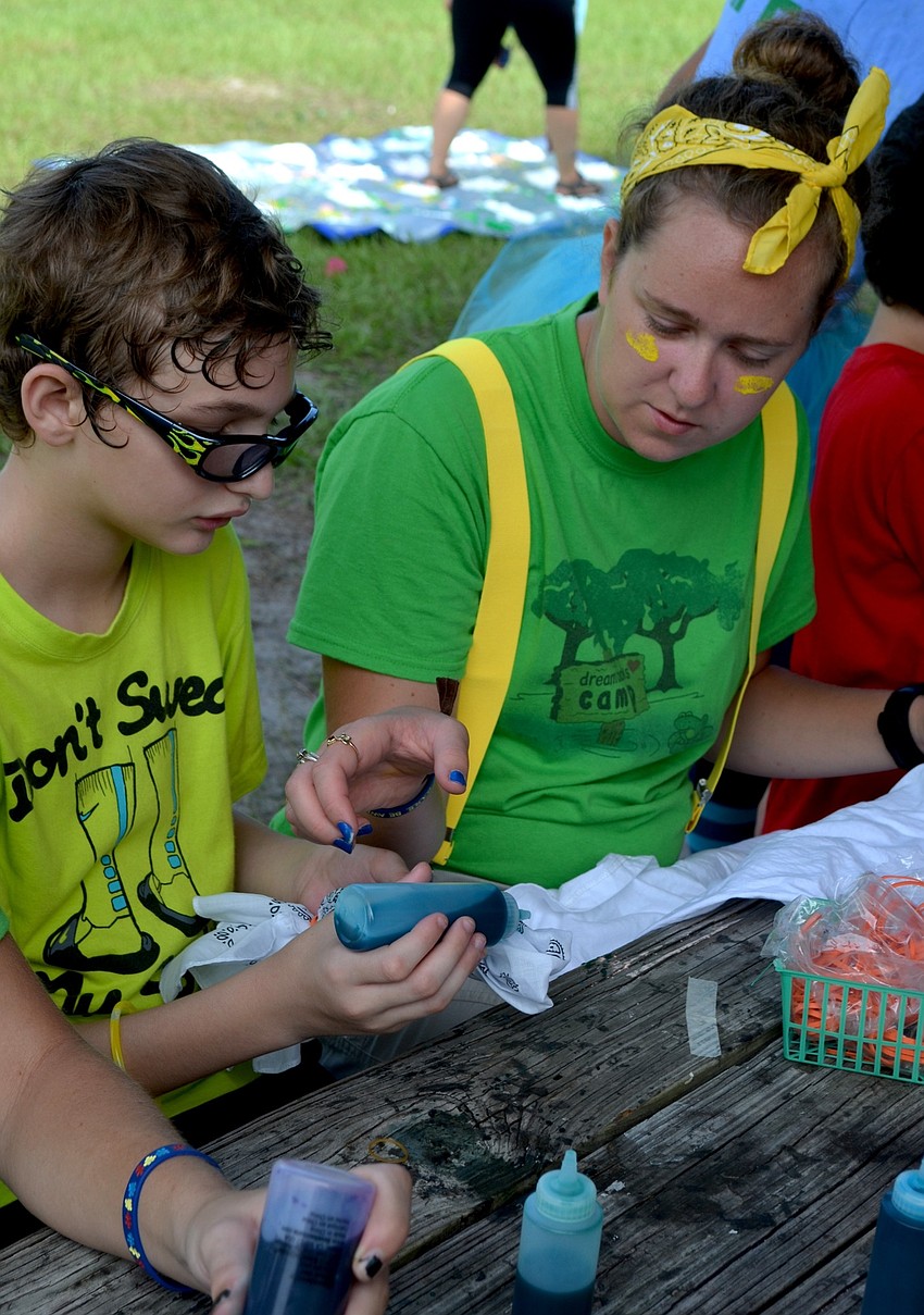 Thomas Valery takes craft lessons from camp volunteer Lulu McClain.