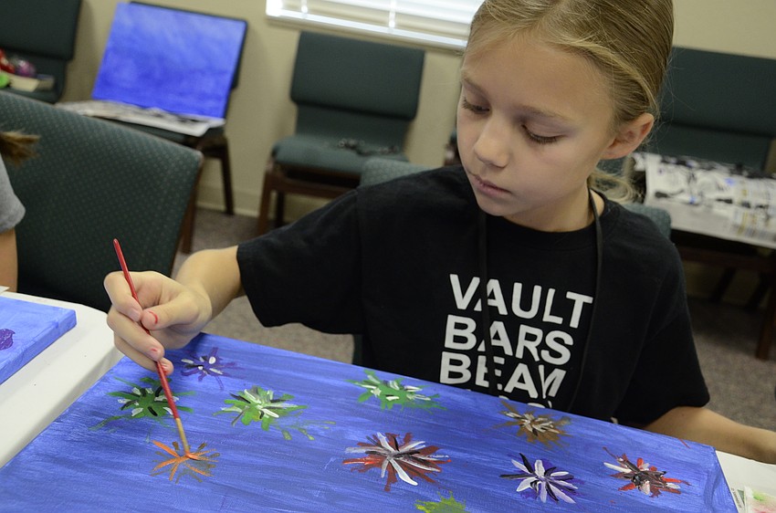 Alana Price paints multi-colored fireworks for her cityscape painting project.