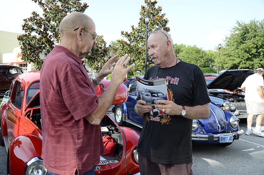 Jerry Worsham from Bradenton and Gary Thorpe from Cortez discuss replacing the wheels on vintage Volkswagen Beetles. Both men own Beetle models; Thorpe owns the 1979 red model behind the two men.