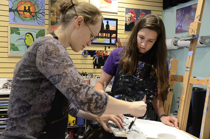 Natalia Akhmetova and Laura Whalen help students dry their modge-podged newspaper.