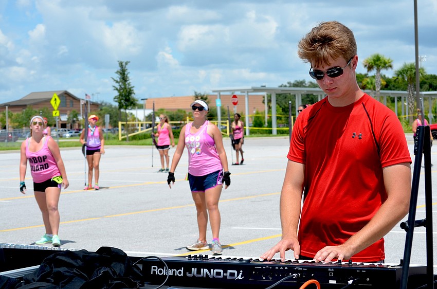 Micah Deyoung focuses on the keyboard as his band mates march behind him.
