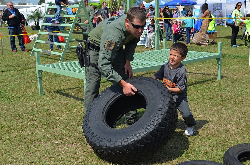 Deputy Lyle Kenney helps Nicholas Still flips over a tire during the obstacle course.