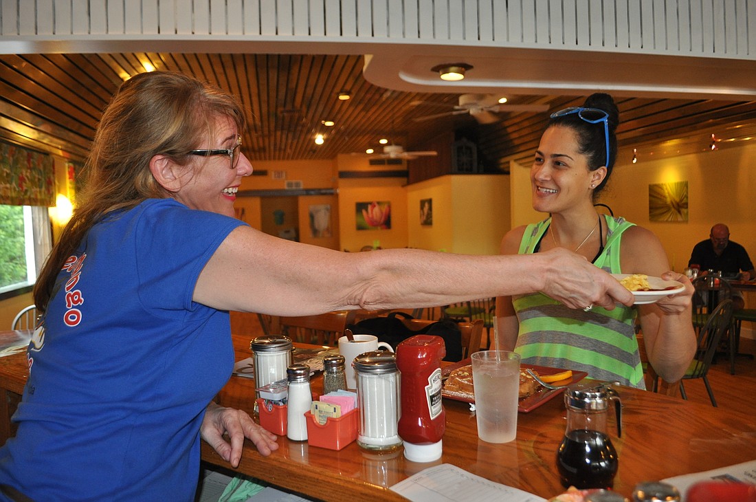 Toasted Mango staff member Suzanne Sementilli serves breakfast to tourist Nicole Gonzalez, who is visiting from Ft. Lauderdale.
