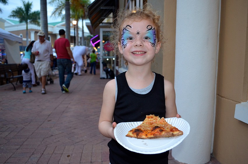 Five-year-old Rhaegan Moore snacks on pizza with a painted face.