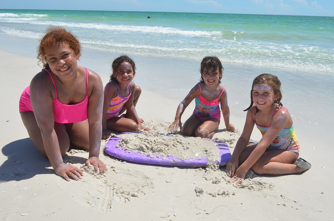 Preia Hayes, 9, and sister, Iyleigh, 6, with Lilly Gerling, 4, and sister Grace, 6 enjoy a rare sunny day at a Longboat beach.
