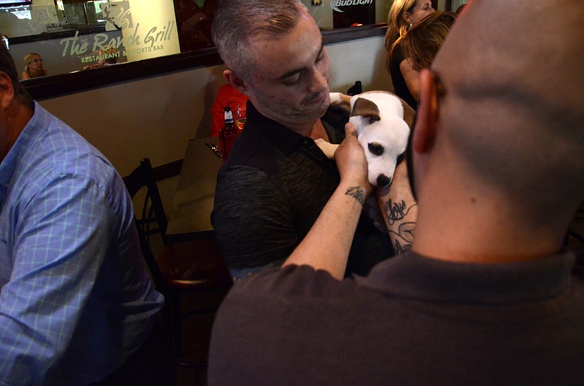 Roger Capote pets Patches while Tony Pinho holds the husky mix puppy.
