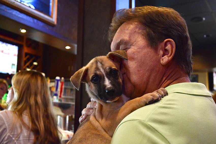 Larry Angst cuddles up to a husky mix puppy available for adoption at Nate's Honor Animal Rescue.