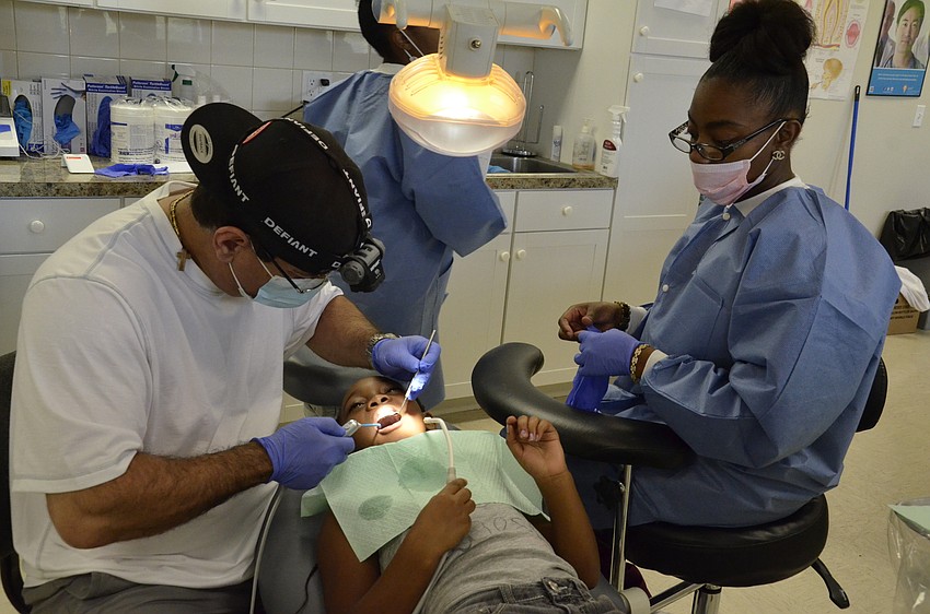 Dr. Fotois Skordas and Meridian student Keyleisha Brannic work on 7-year-old Deneisha Sims' teeth.