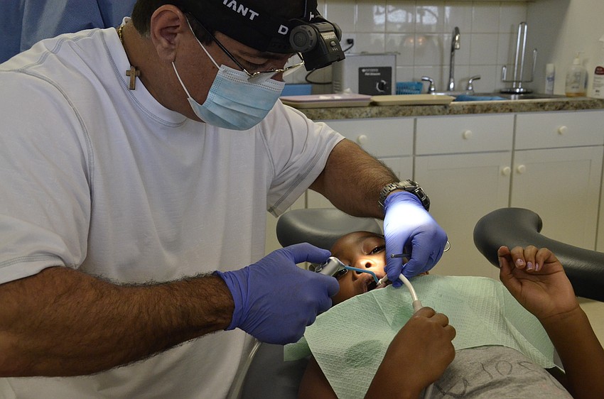 Dr. Fotois Skordas wets 7-year-old Deneisha Sims' teeth.