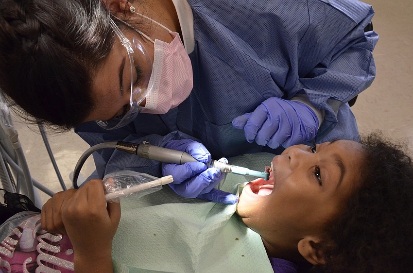 Megan Bardwick grinds off build-up on Jaidyn Roberts' teeth.