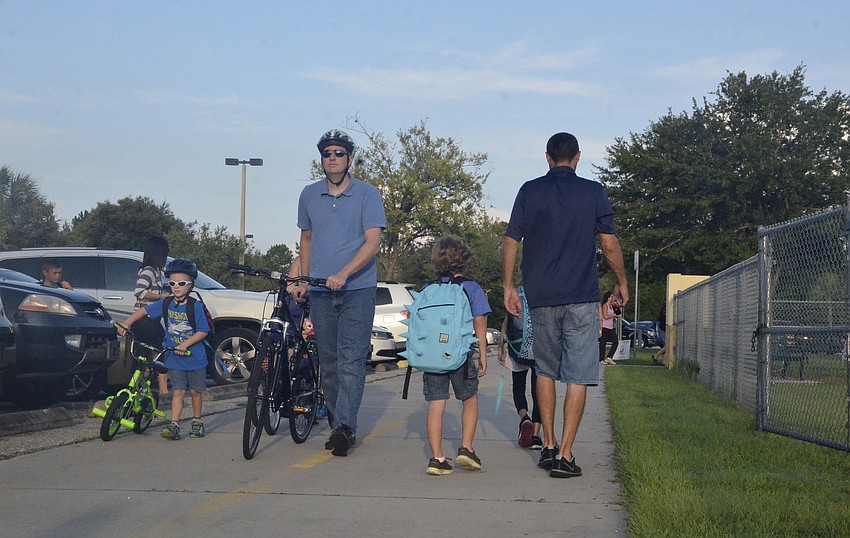 Ryan Mach takes his son, Mason, 5, to lock up his bike in the bike rack. The Mach family, including Carrie, mom, and little sister, Paige, 3, plan to walk or ride bikes to school every day. 