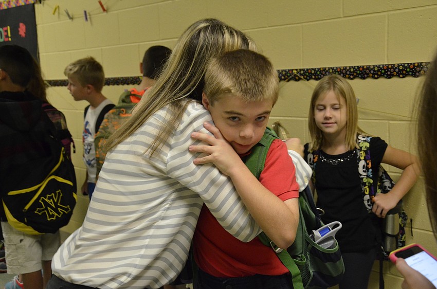 Laura Sherry gives her son, Luke, 8, one last hug before he starts his third-grade class.