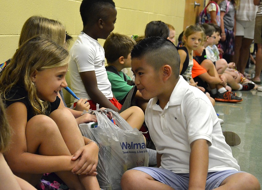 Kylie Caffrey, 8, talks with fellow third-grader Justin Tran, 8, as they sit and wait for the bell to ring.
