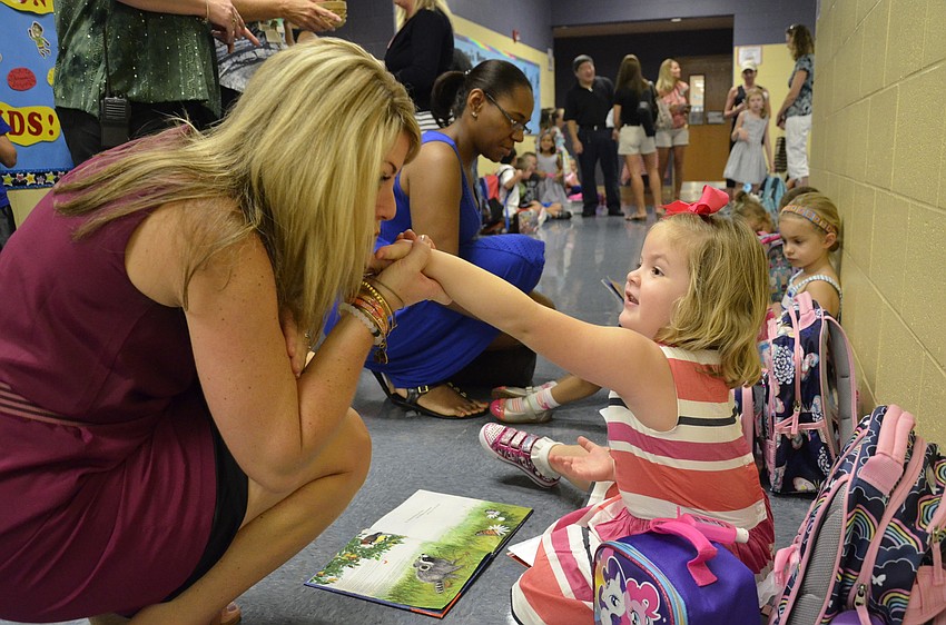 Kristi Dyer gives her daughter, Ella, 4, a kiss before Ella leaves for class. Dyer teaches third grade at McNeal. 