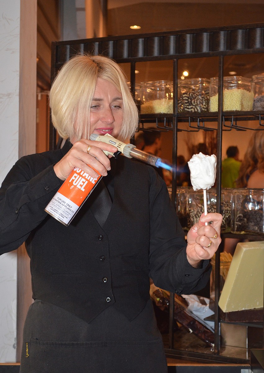 Patricia Robson uses a blow torch to toast a double-dipped marshmallow which is a marshmallow dipped in chocolate with Heath bar bits and nuts before being dipped again in a marshmallow coating and toasted.