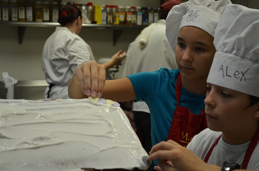 Ally Chawkins adds candy shingles to the roof of the gingerbread house.