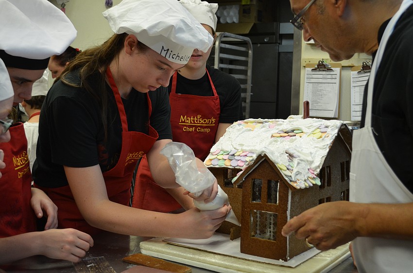 Michelle Lane pipes icing onto the gingerbread house to add a front porch step.